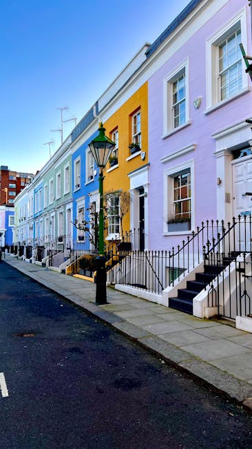 A row of multi-story residential buildings painted in pastel shades of purple, yellow, white, and pink, featuring detailed architectural elements such as decorative moldings, bay windows, and balconie